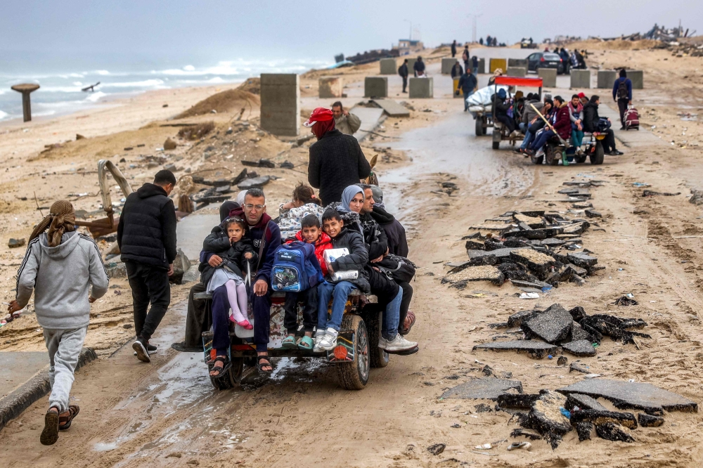 People ride in a horse-drawn cart as they approach the concrete barriers of the Netzarim corridor between Gaza City and Nuseirat. — AFP