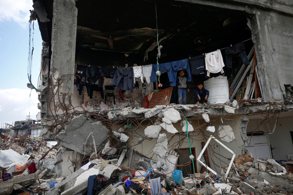 Palestinian children look out from the ruins of their house in Jabalia refugee camp in the northern Gaza Strip on Thursday. — Reuters