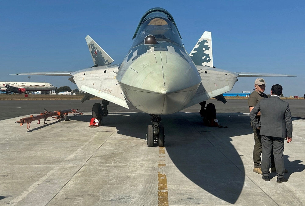 Officials stand next to a parked Russian Sukhoi Su-57 stealth fighter jet during the Aero India 2025 air show in Bengaluru. - Reuters