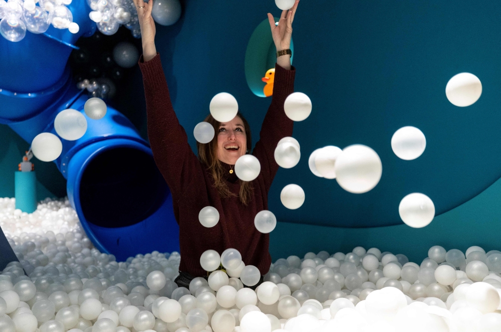 Museum founder Andrea Golubic poses inside a pool full of small white balls at the HaHaHouse museum of laughter in central Zagreb, on January 21, 2025.   The 450-square-metre (4,844-square-feet) museum, which opened in January, offers eight interactive zones and has also an educational part featuring the history of humour from ancient to modern times and via different formats -- theatre, film or Internet.  (Photo by Damir SENCAR / AFP)

