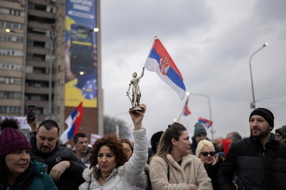 A woman holds a statuette of Lady Justice holding a Serbian national flag, in Kragujevac. — Reuters 