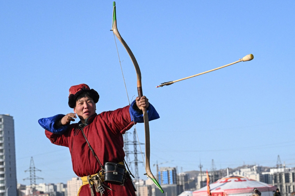 A man in a traditional Mongolian costume shoots an arrow during the “Mongols Nomadic Winter Festival” at National Park in Ulaanbaatar, the capital of Mongolia on February 20, 2025. (Photo by JADE GAO / AFP)

