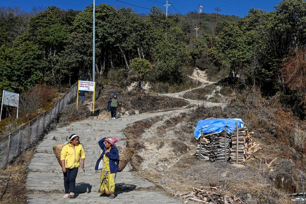 In this photograph taken on January 21, 2025, porters look for customers along a path leading to the Pathibhara Devi temple at Taplejung district, in Koshi province of Nepal. They appear tranquil when soaring above Himalayan forests, but a string of cable car projects in Nepal have sparked violent protests with locals saying environmental protection should trump tourism development. (Photo by Prakash MATHEMA / AFP)

