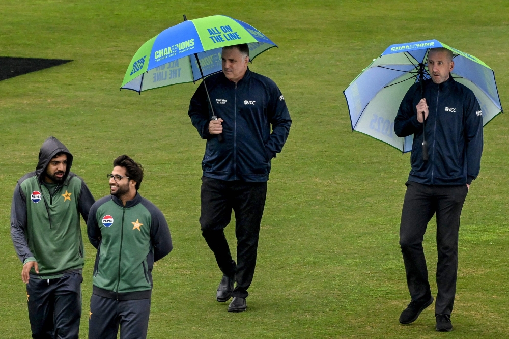 Pakistan's Imam-ul-Haq (2L) speaks with teammate Haris Rauf (L) as field umpires Adrian Holdstock (2R) and Michael Gough inspect the outfield after rain delayed the start of the ICC Champions Trophy one-day international (ODI) cricket match between Pakistan and Bangladesh at the Rawalpindi Cricket Stadium in Rawalpindi on February 27, 2025. Overnight rain which continued on and off delayed the toss in the Champions Trophy dead-rubber Group A match between hosts Pakistan and Bangladesh at Rawalpindi Stadium on February 27. (Photo by Farooq NAEEM / AFP)

