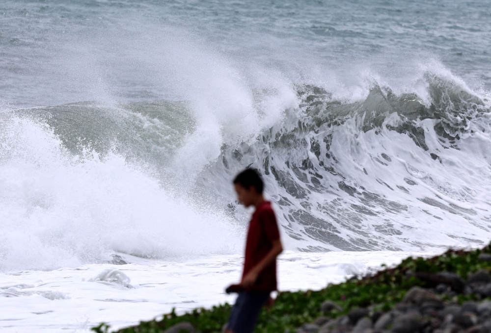A child walks on a beach facing the swell as the tropical system "Garance" approaches in Saint-Denis de la Reunion, on the French overseas territory island of La Reunion on February 26, 2025. The island of Reunion will be placed under a red cyclone alert from 7.00 pm on February 27, 2025, when cyclone Garance, described as "dangerous" by Meteo France, is due to arrive, the prefecture has announced. If it maintains its current trajectory, the cyclone should pass "less than 50 km" inland, "during the evening of February 27 to 28", or even early February 28 morning, at least at the stage of a tropical cyclone", said the prefecture in a statement published early February 27 morning. (Photo by Richard BOUHET / AFP)
