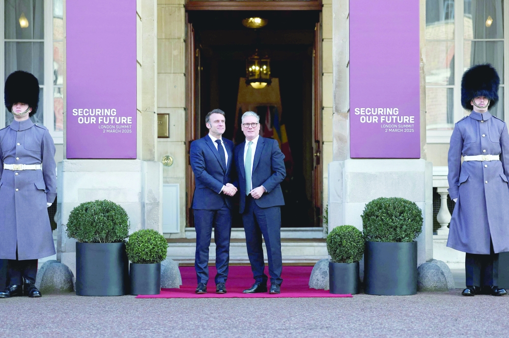 Britain's Prime Minister Keir Starmer (R) greets France's President Emmanuel Macron (L) as he arrives to attend a summit held at Lancaster House in central London. — AFP