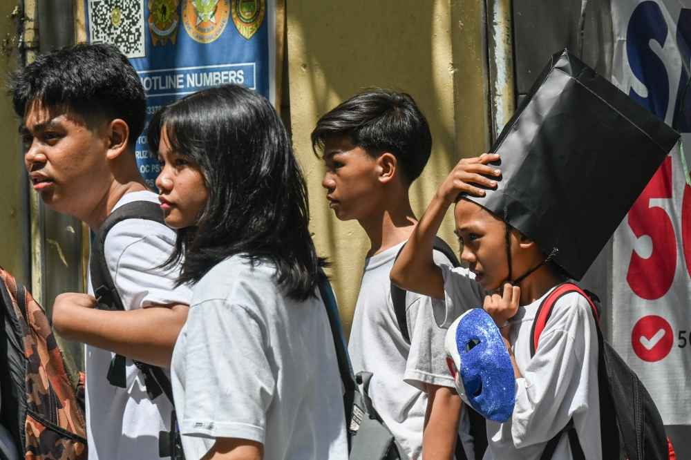 A student uses a paper bag to protect himself from the heat as he leaves school in Ma