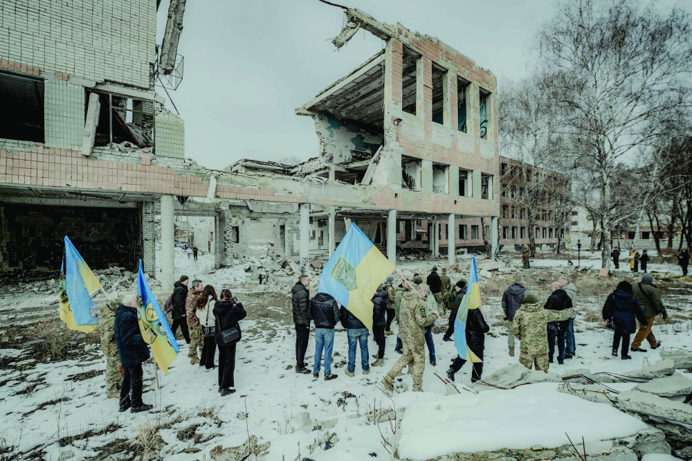 Ukrainian soldiers and relatives of fallen soldiers walk with national flags to the sites of airstrikes, in Kharkiv. — AFP 