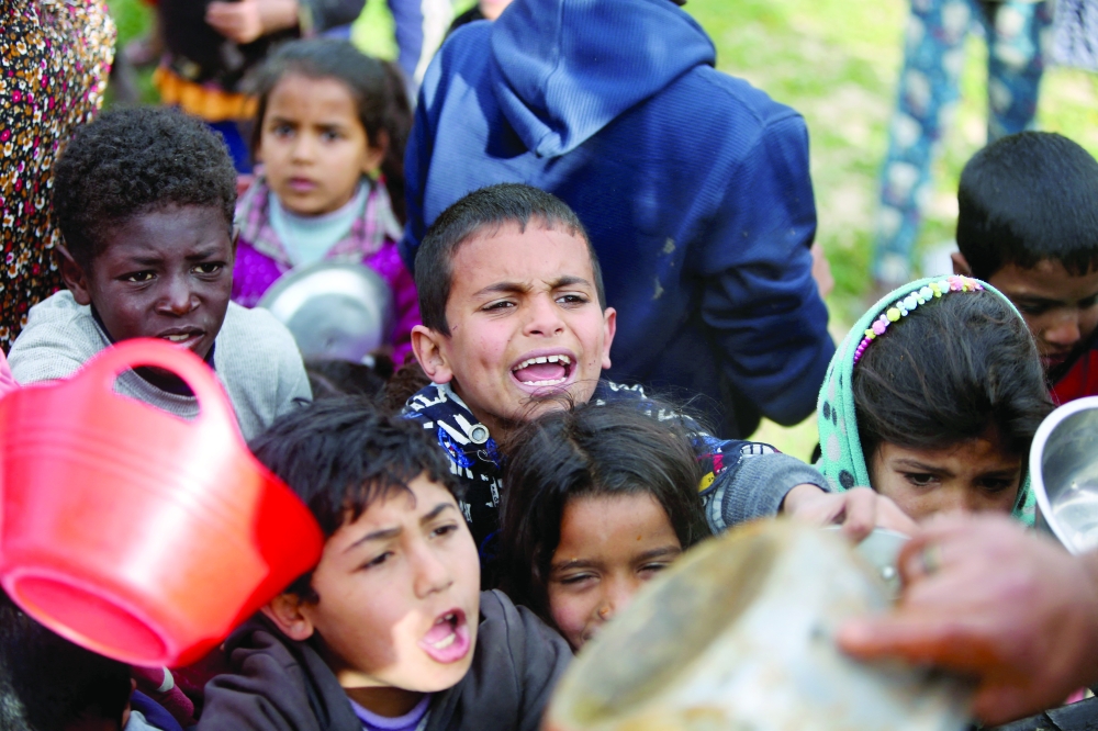 Palestinian children gather to receive food cooked by a charity kitchen, in Khan Yunis. — Reuters