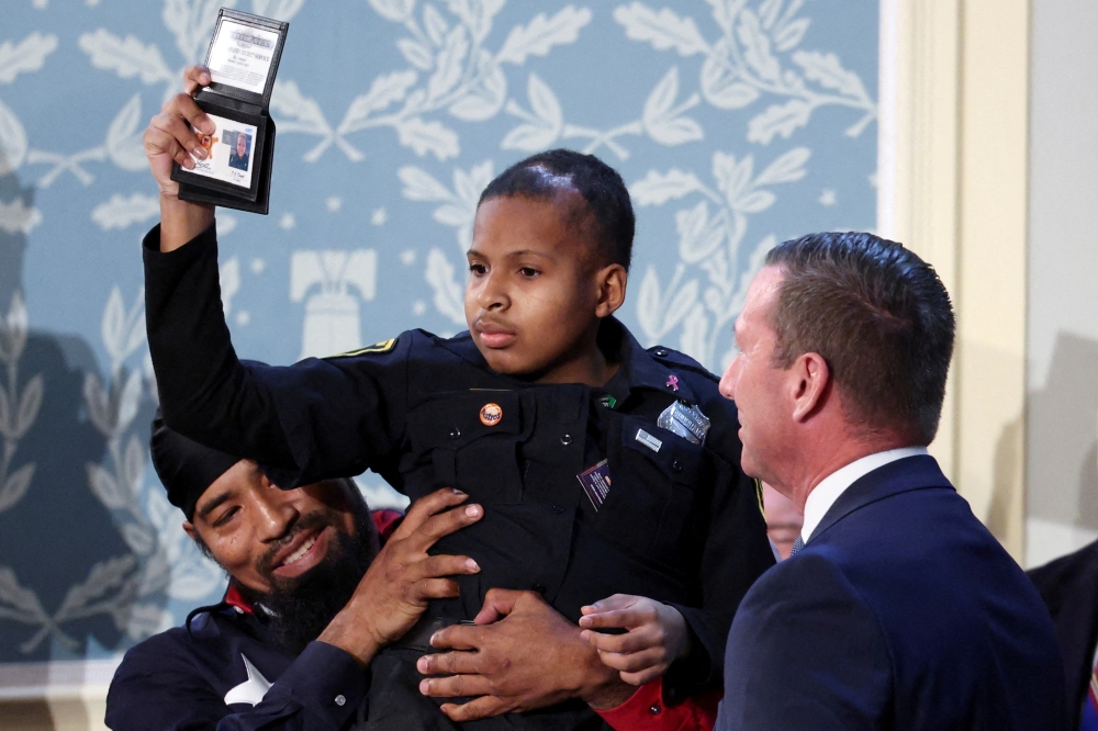 Cancer survivor Devarjaye "DJ" Daniel gestures as he is made an honorary Secret Service agent
