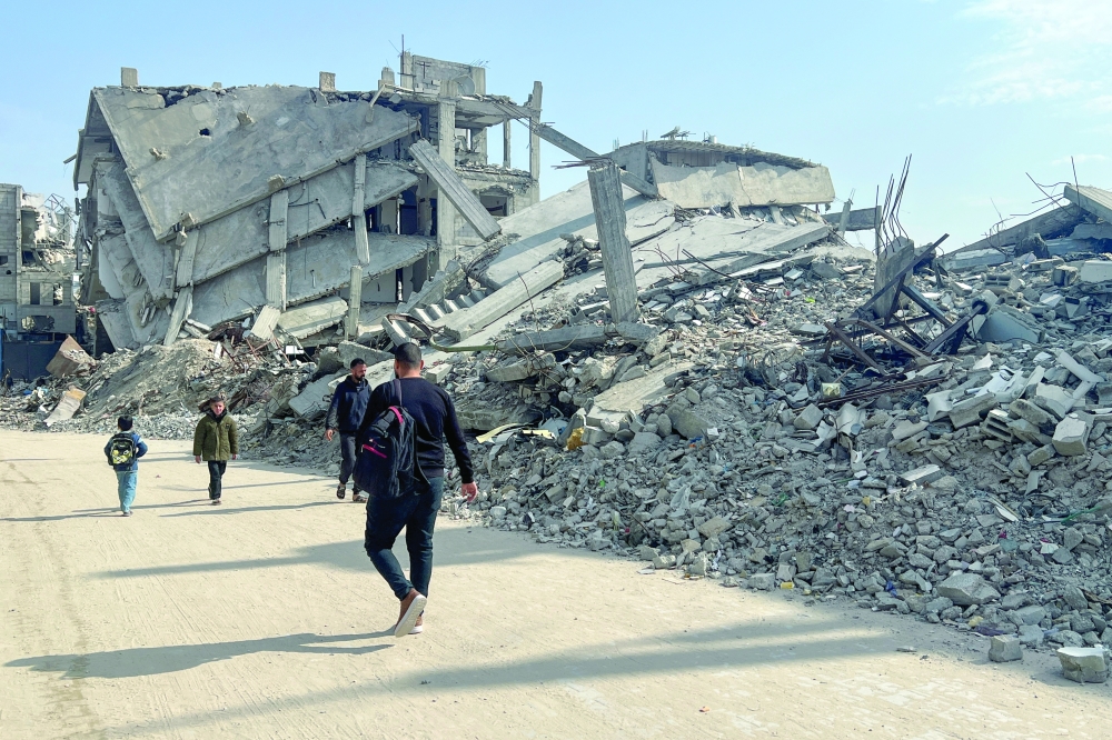 Palestinians walk past the rubble of destroyed houses, amid a ceasefire between Israel and Hamas, in Khan Yunis in the southern Gaza Strip. — Reuters