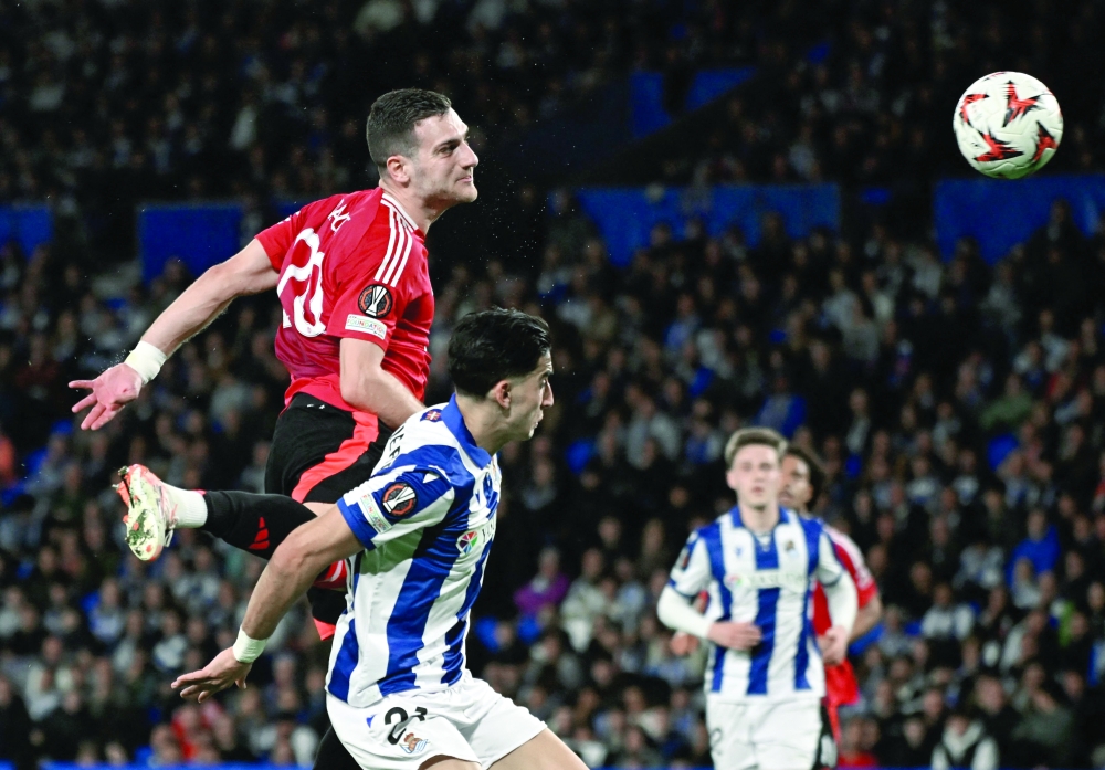 Manchester United's Portuguese defender #20 Diogo Dalot (top) goes for a header challenged by Real Sociedad's Moroccan defender #21 Nayef Aguerd during the UEFA Europa League Round of 16 first let football match between Real Sociedad and Manchester United at Anoeta Stadium in San Sebastian on March 6, 2025. 