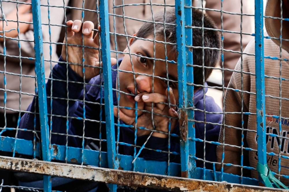 A Palestinian boy stands next to a fence as he and others gather to receive bread from a bakery, in Khan Younis, in Gaza, on Sunday. - Reuters