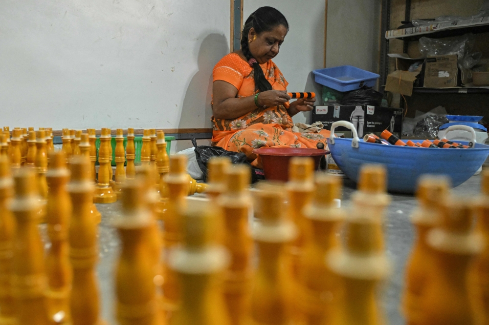 This photograph taken on February 26, 2025 shows an artisan making wooden lacquerware at a toy manufacturing unit, in Channapatna in the Ramanagara district of India's Karnataka state. India's town of Channapatna is famed for its wood and lacquer toys, carved from ivory wood from a local deciduous tree -- and dipped in brightly coloured dye from natural ingredients including turmeric and indigo. Channapatna's toymaking industry dates back to the 1700s when Tipu Sultan, ruler of the then kingdom of Mysore, asked artists from Persia to train the locals. - To go with AFP story INDIA-CULTURE-TOYS
 (Photo by Idrees MOHAMMED / AFP) / To go with AFP story INDIA-CULTURE-TOYS

