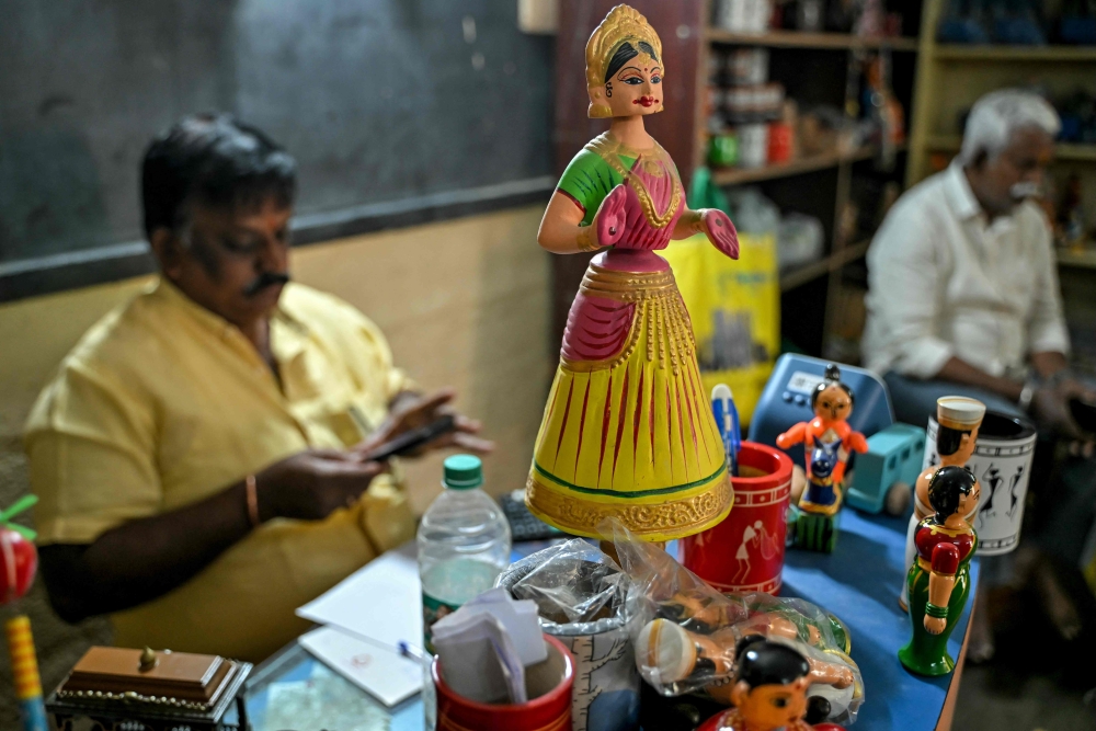 This photograph taken on February 26, 2025 shows a hand-painted Channapatna doll displayed for sale at artisan Venkatesh's toy store in Channapatna in the Ramanagara district of India's Karnataka state. India's town of Channapatna is famed for its wood and lacquer toys, carved from ivory wood from a local deciduous tree -- and dipped in brightly coloured dye from natural ingredients including turmeric and indigo. Channapatna's toymaking industry dates back to the 1700s when Tipu Sultan, ruler of the then kingdom of Mysore, asked artists from Persia to train the locals. - To go with AFP story INDIA-CULTURE-TOYS
 (Photo by Idrees MOHAMMED / AFP) / To go with AFP story INDIA-CULTURE-TOYS

