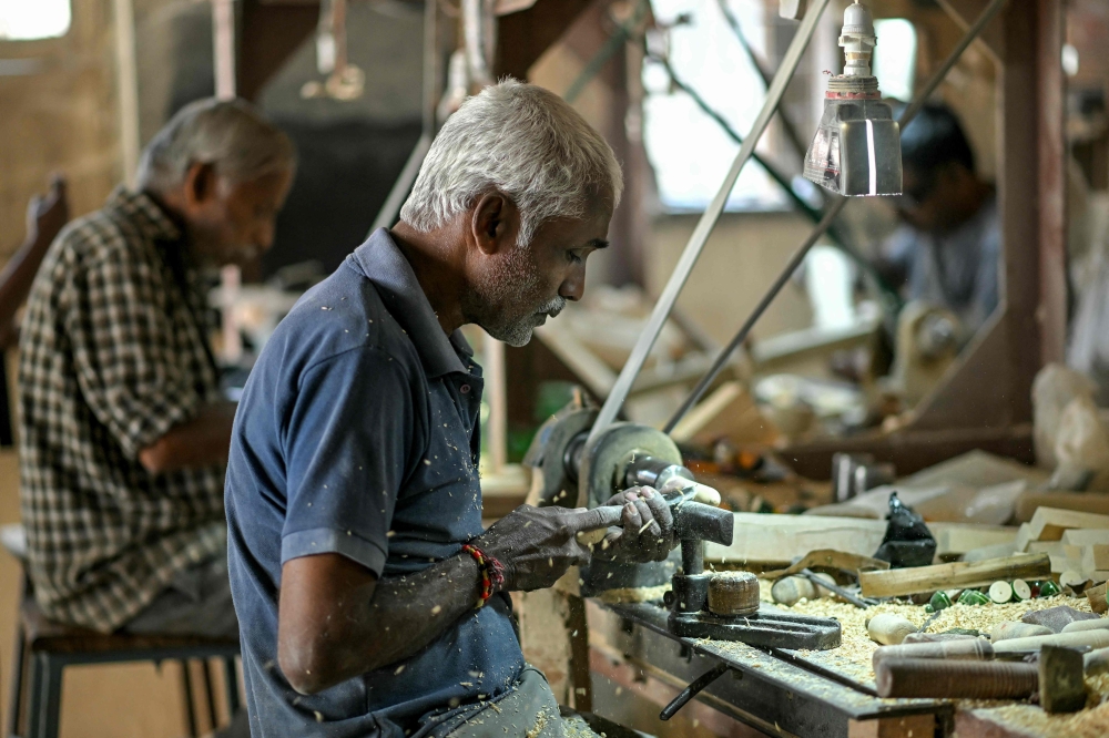 This photograph taken on February 26, 2025 shows artisans making wooden toys at a toy manufacturing unit, in Channapatna in the Ramanagara district of India's Karnataka state. India's town of Channapatna is famed for its wood and lacquer toys, carved from ivory wood from a local deciduous tree -- and dipped in brightly coloured dye from natural ingredients including turmeric and indigo. Channapatna's toymaking industry dates back to the 1700s when Tipu Sultan, ruler of the then kingdom of Mysore, asked artists from Persia to train the locals. - To go with AFP story INDIA-CULTURE-TOYS
 (Photo by Idrees MOHAMMED / AFP) / To go with AFP story INDIA-CULTURE-TOYS

