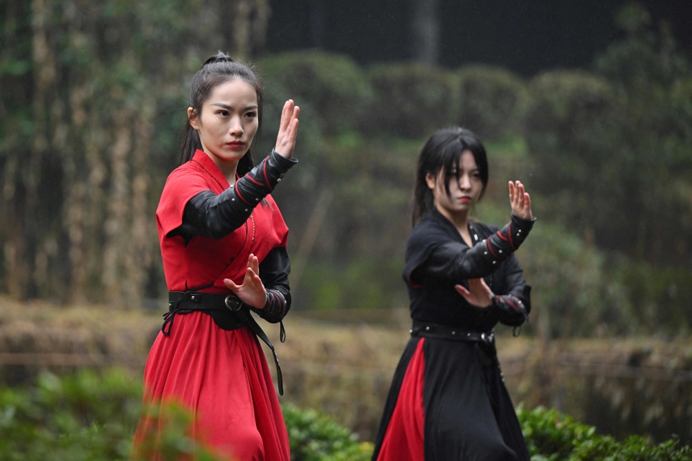 This photo taken on February 21, 2025 shows Duan Ruru (L), a founding member of the Emei Kung Fu Girls, and Liu Qiao demonstrating their martial art movements at the Zhongfei temple in Emeishan, China's southwestern Sichuan province. The ancient Emei school in the mountains of Sichuan is thought to have welcomed a higher proportion of women and girls, but has struggled in recent years to raise its profile. That is now changing thanks to a group of women from Generation Z, who mesh skilful swordwork with social media smarts to help put the sect back on the map.
 - To go with 'CHINA-WOMEN-KUNG FU, FOCUS' by Mary YANG
 (Photo by Adek BERRY / AFP) / To go with 'CHINA-WOMEN-KUNG FU, FOCUS' by Mary YANG

