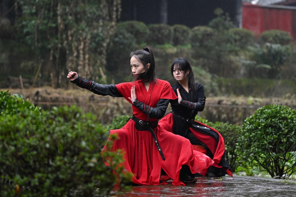 This photo taken on February 21, 2025 shows Duan Ruru (L), a founding member of the Emei Kung Fu Girls, and Liu Qiao demonstrating their martial art movements at the Zhongfei temple in Emeishan, China's southwestern Sichuan province. The ancient Emei school in the mountains of Sichuan is thought to have welcomed a higher proportion of women and girls, but has struggled in recent years to raise its profile. That is now changing thanks to a group of women from Generation Z, who mesh skilful swordwork with social media smarts to help put the sect back on the map.
 - To go with 'CHINA-WOMEN-KUNG FU, FOCUS' by Mary YANG
 (Photo by Adek BERRY / AFP) / To go with 'CHINA-WOMEN-KUNG FU, FOCUS' by Mary YANG

