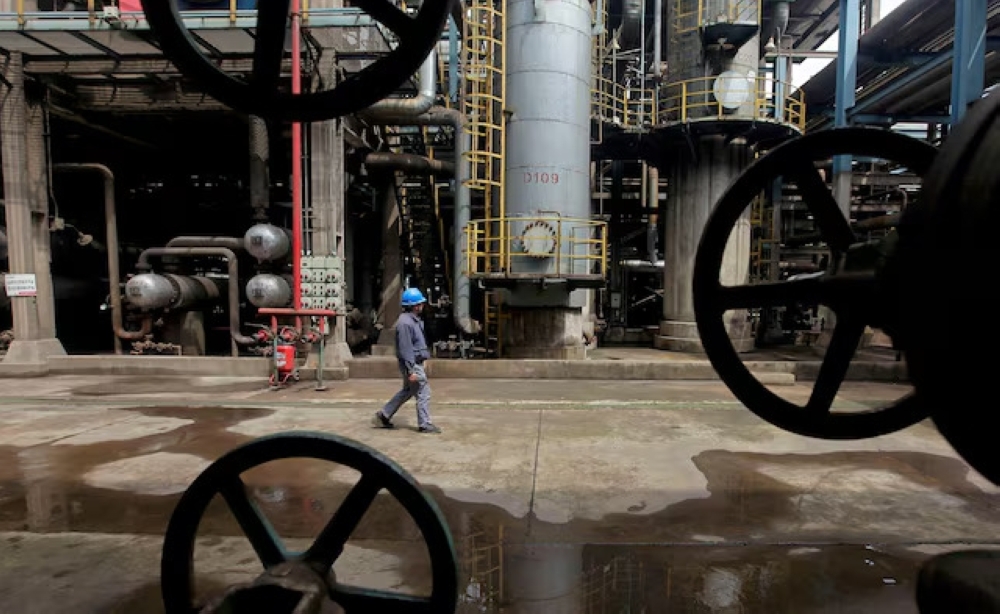 A worker walks past oil pipes at a refinery in Wuhan, Hubei province. — Reuters