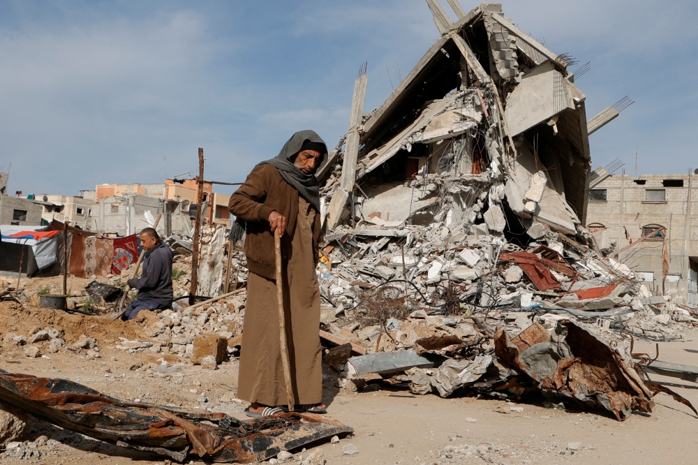 A Palestinian man walks near rubble of houses destroyed during the Israeli offensive, in Rafah, in the southern Gaza Strip, March 13, 2025. REUTERS/Hatem Khaled