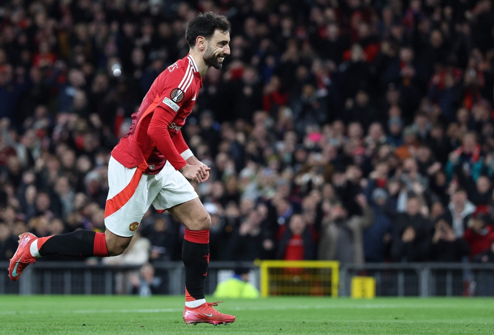 Manchester United's Portuguese midfielder #08 Bruno Fernandes celebrates after scoring from the penalty spot to equalise during the UEFA Europa League Last 16 Second Leg football match between Manchester United and Real Sociedad at Old Trafford stadium in Manchester, north west England, on March 13, 2025. (Photo by Darren Staples / AFP)

