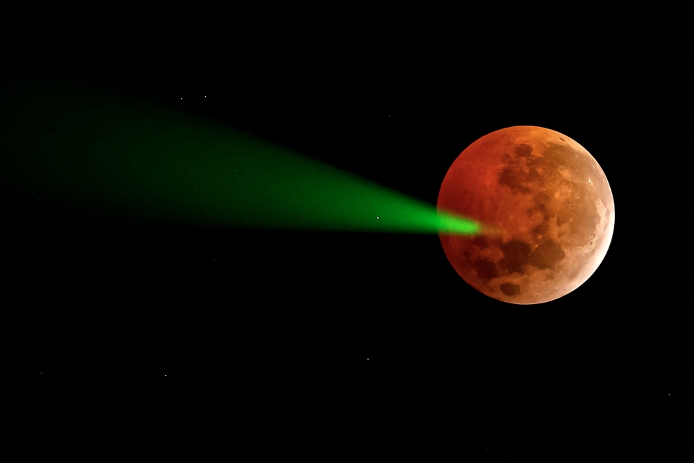 The full moon eclipse is targeted with a laser from the Foster Observatory telescope in Santiago, Chile