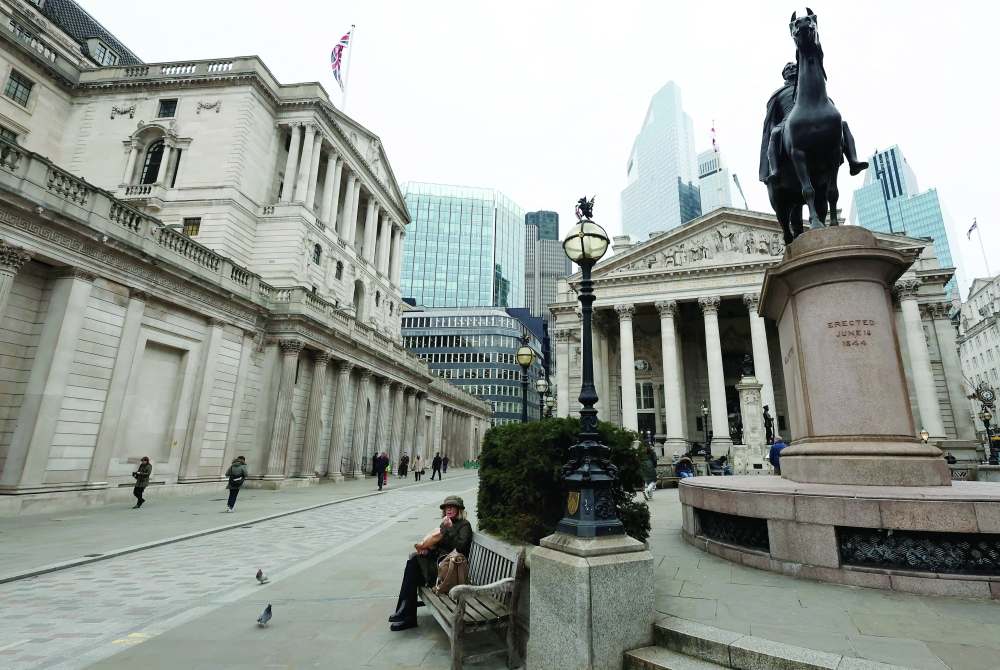 A person sits near the Bank of England building in London, Britain. — Reuters