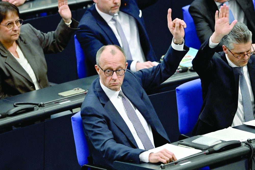 Friedrich Merz (C), leader of Germany's conservative Christian Democratic Union (CDU) party, and officials raise hands during a vote at a session of the Bundestag, in Berlin. — AFP