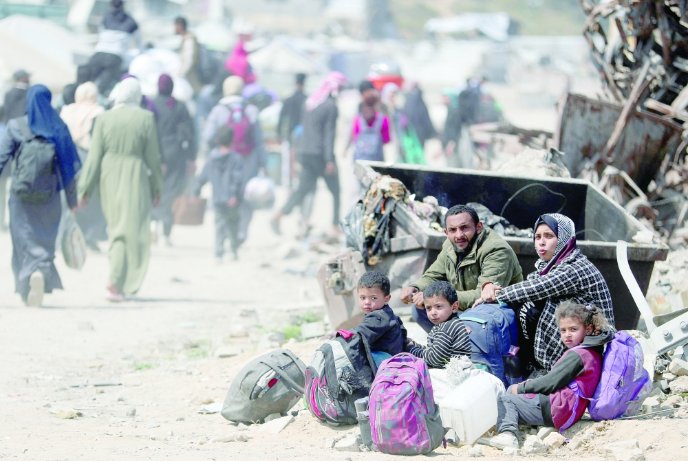 People sit as Palestinians make their way to flee their homes, Gaza. — Reuters
