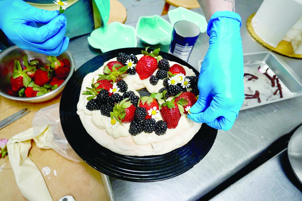 Annie Clemmons, owner of online bakery Chapman's DC, decorates an eggless pavlova in the ghost kitchen she uses for her business in Silver Spring, Maryland, on March 17, 2025.  Since avian flu turned eggs into a luxury item, pastry chef Annie Clemmons has spent countless hours in her Maryland workshop, racking her brains about how to replace them in her recipes. The increasing number of outbreaks of avian flu on US farms has made eggs an expensive - and rare - commodity. 