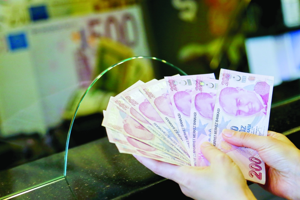 A money changer holds Turkish lira banknotes at a currency exchange office in Ankara. — Reuters