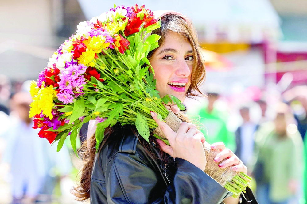 A woman holds a bouquet of flowers outside the Tajrish Bazaar in central Tehran as people celebrate Nowruz, the Persian New Year. — AFP