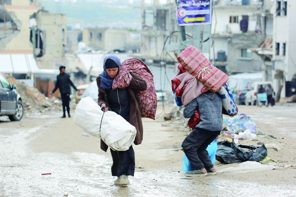 A Palestinian woman carries her belongings as she flees Beit Lahia in the northern Gaza Strip on Friday. — AFP