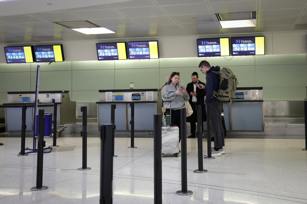 Travellers with cancelled British Airways flights stand near the closed BA check-in area 