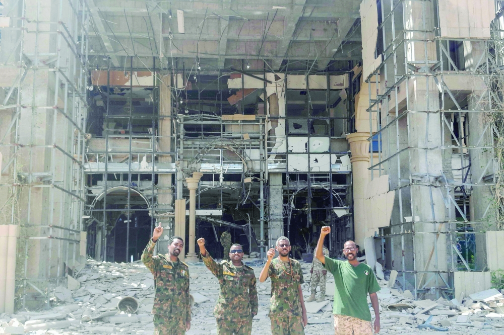 Soldiers of the Sudanese army pose at the damaged presidential palace, in Khartoum. — AFP