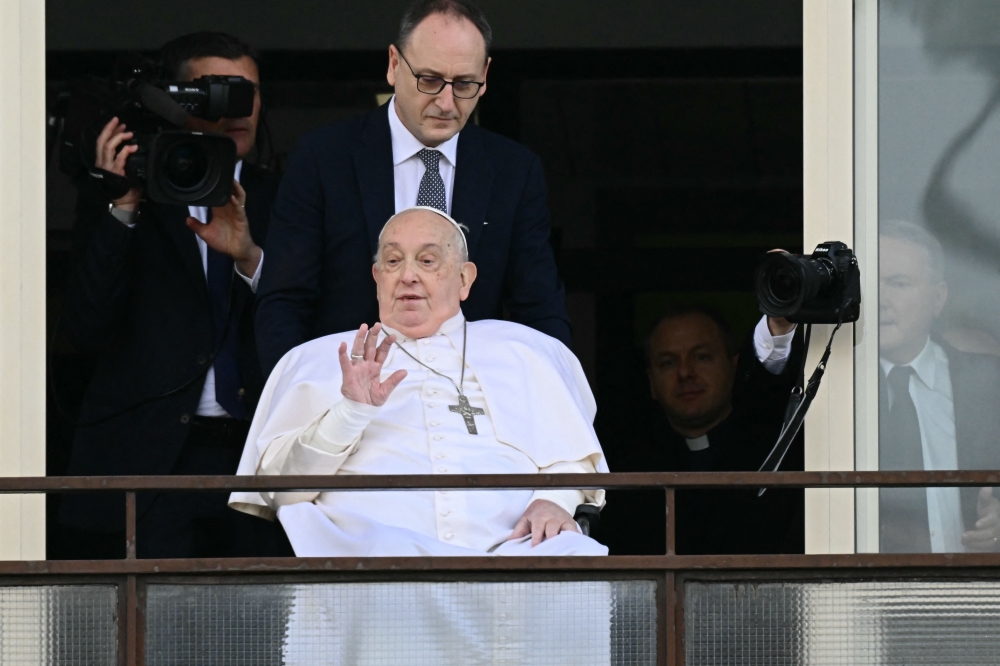 TOPSHOT - Pope Francis waves from a window of the Gemelli hospital before being discharged following a five weeks hospitalization for pneumonia, in Rome on March 23, 2025. Pope Francis is to leave hospital todayand return to his residence in the Vatican, where he is to spend "at least two months" recovering, one of his doctors announced during a press conference on March 22, 2025.
