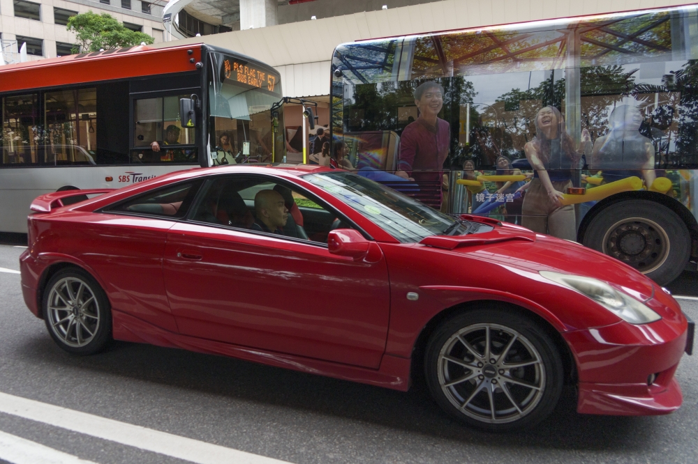 A car and buses share a street in Singapore, March 11, 2025. (Chang W. Lee/The New York Times)