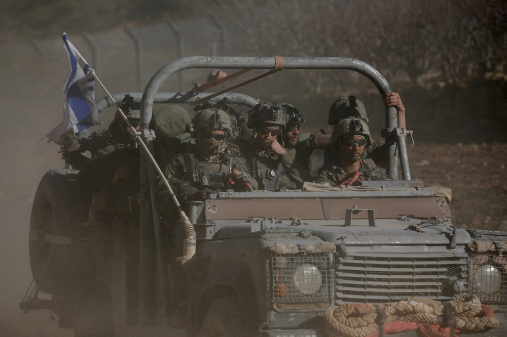 An Israeli military vehicle rides on the Golan Heights side of the ceasefire line with Syria. — Reuters