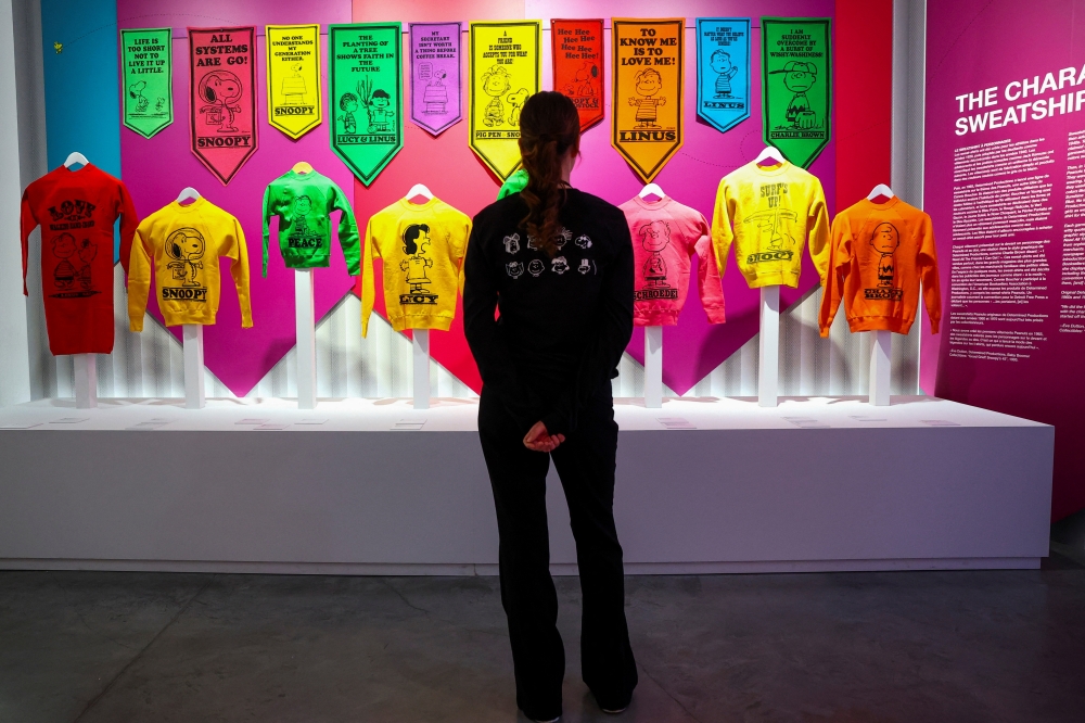 A woman looks at jerseys with Snoopy and other characters from "Peanuts", displayed as part of the "Snoopy In Style" exhibition to mark the Peanuts comic strip's 75th anniversary in Paris, France, March 20, 2025. REUTERS/Gonzalo Fuentes
