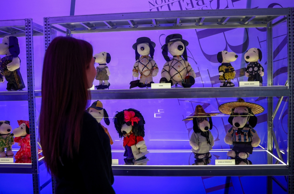 A woman looks at Snoopy figurines displayed as part of the "Snoopy In Style" exhibition to mark the Peanuts comic strip's 75th anniversary in Paris, France, March 20, 2025. REUTERS/Gonzalo Fuentes
