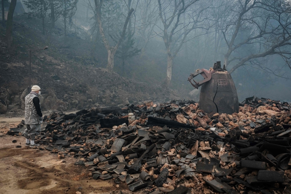 A monk looks at a cracked temple bell remaining, at Gounsa Temple in Uiseong. — AFP