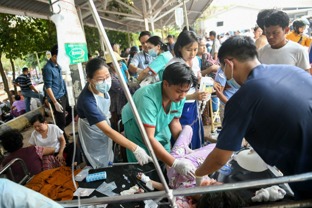 Medical workers treat an earthquake survivor on a bed in the compound of a hospital in Naypyidaw on March 28, 2025