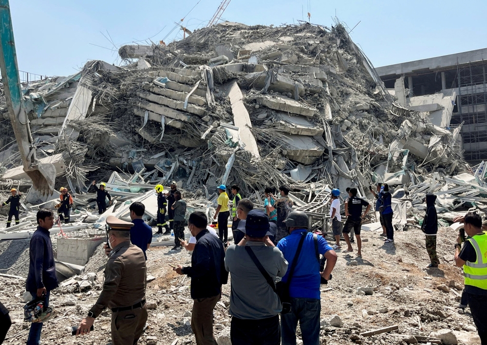 People stand near the site of a collapsed building after a strong earthquake struck central Myanmar on Friday. — Reuters