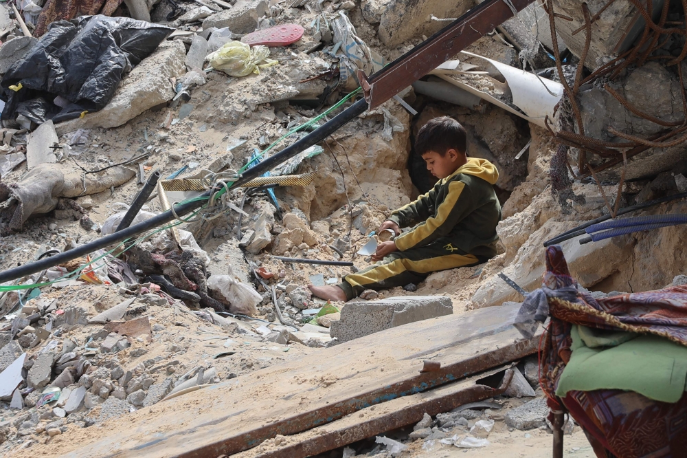 A Palestinian boy plays amidst the debris