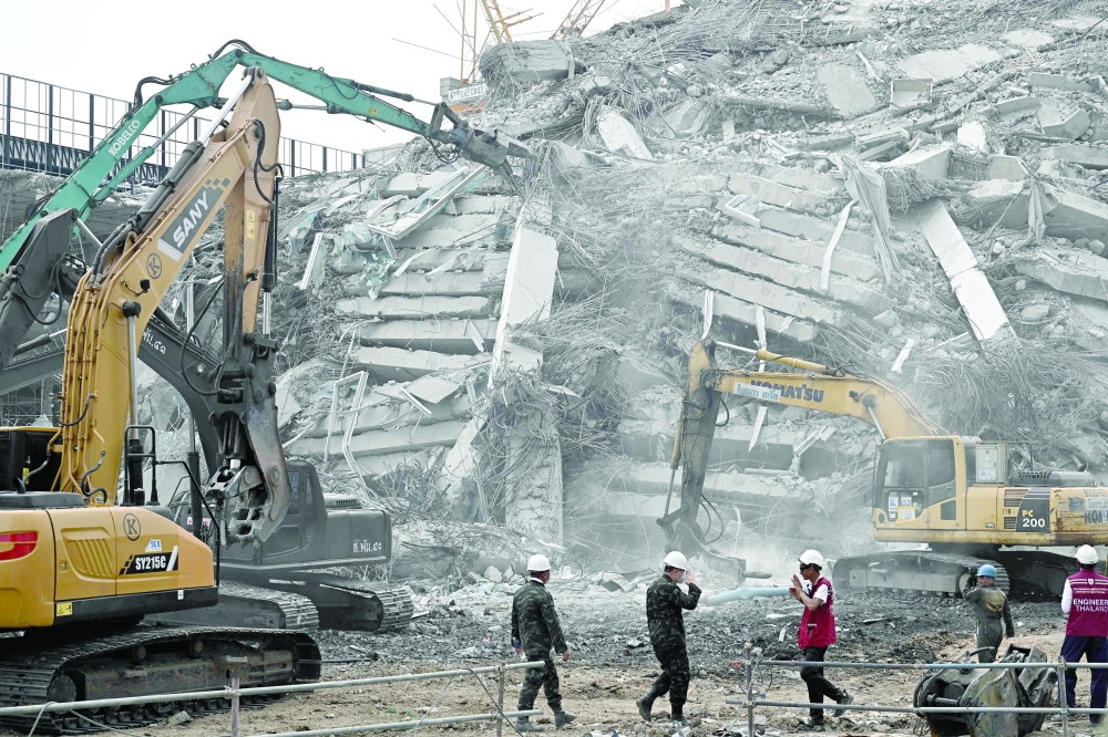 Machinery is used to clear the rubble at the site of an under-construction building collapse in Bangkok. — AFP