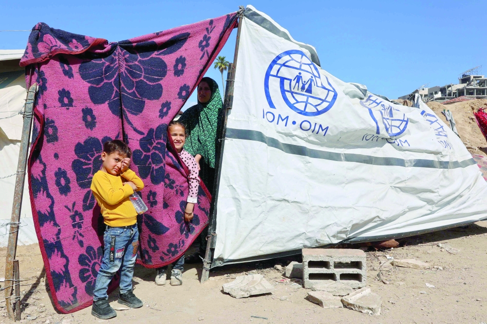 A Palestinian family stands outside their makeshift tent, in Gaza City. — AFP