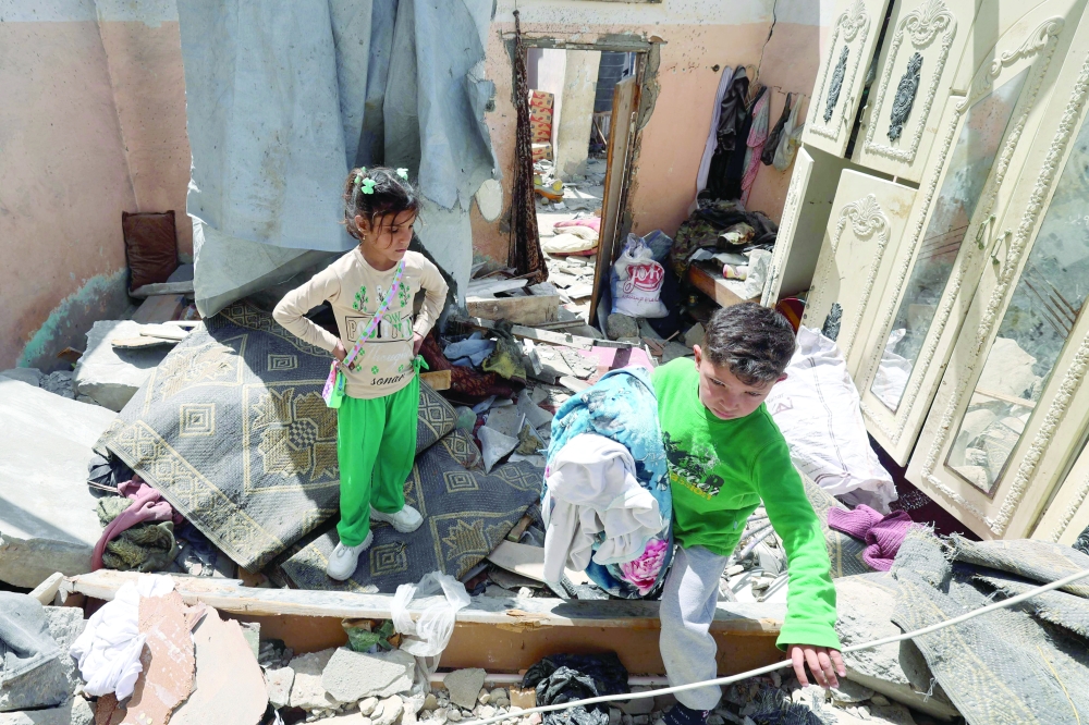 Palestinian children salvage items from the rubble of a house that was destroyed in an Israeli air strike in Khan Yunis on Monday. — AFP