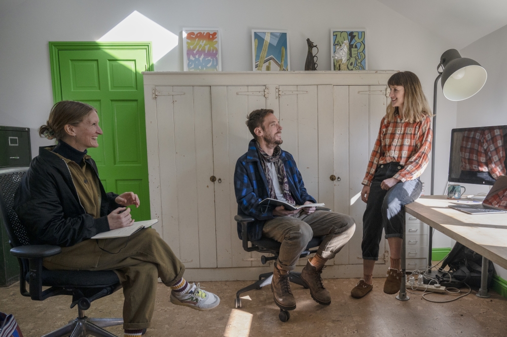 From left, Nancy Waters with Joe Ryrie and his wife, Daisy Greenwell, in their home office in Suffolk, England on March 4, 2025. (Mary Turner/The New York Times)