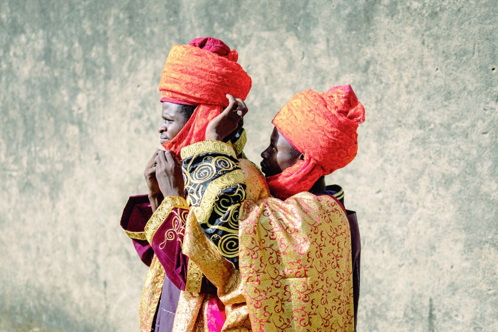 A member of the royal guard helps another one arrange his costume before the Durbar. — AFP