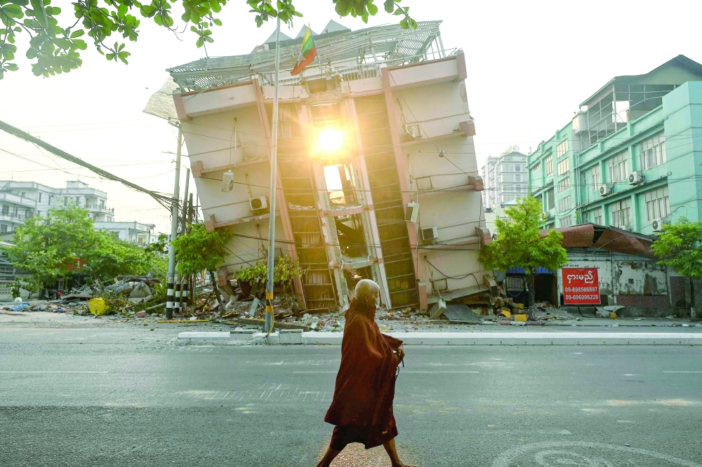 A monk walks past a collapsed building in Mandalay on Tuesday, a few days after the deadly Myanmar earthquake. — AFP